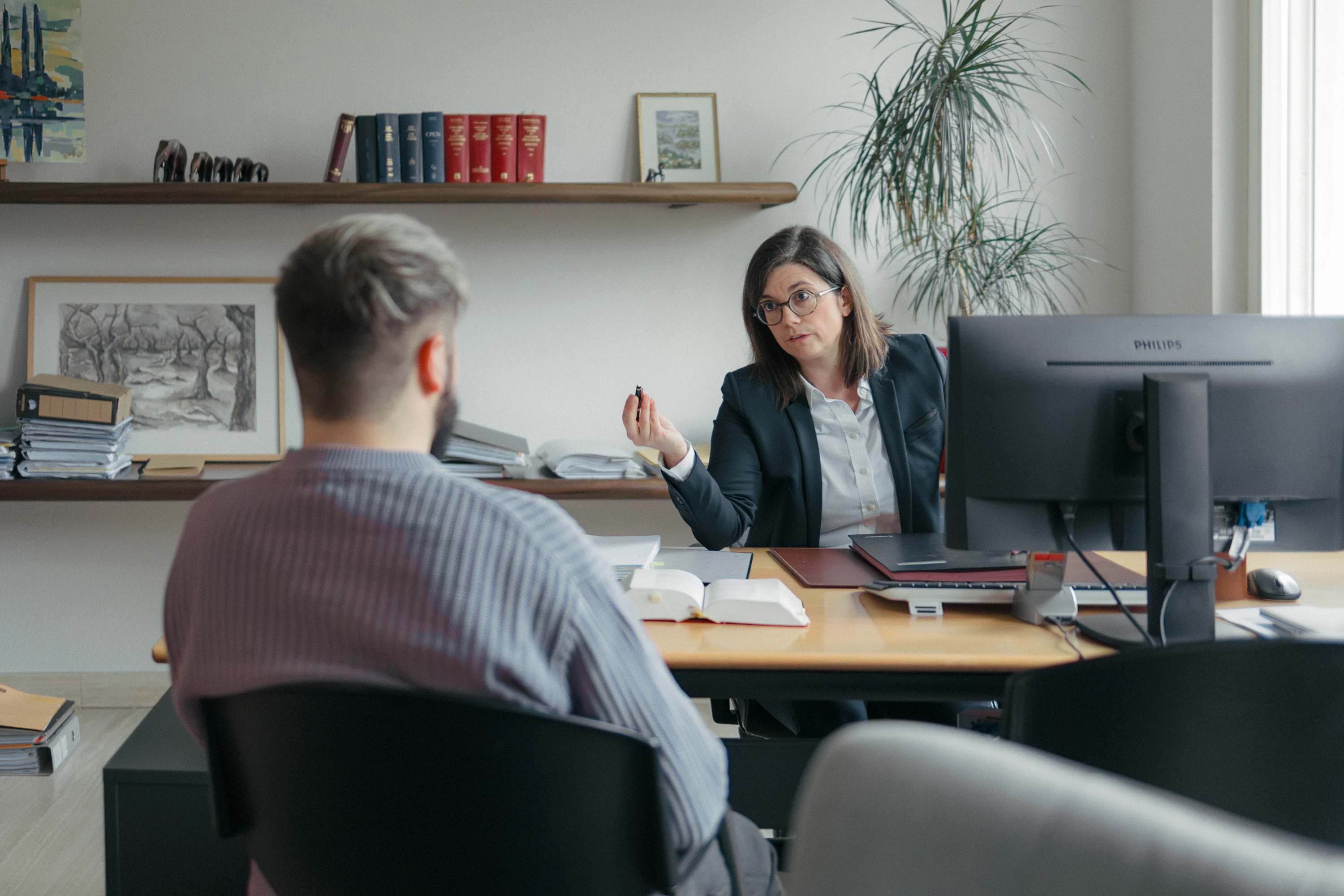 Anne-Sophie Brady assise à son bureau d'avocate en rendez-vous avec un client.